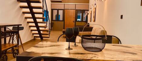 A modern dining area with a wooden table, black chairs, and a staircase.