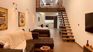 Una sala de estar moderna con un sofá, una mesa de centro y una escalera que lleva a un nivel superior.
