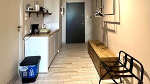 Ένας στενός διάδρομος, με μια μικρή κουζίνα στα αριστερά, ένα παγκάκι στα δεξιά και μια πόρτα στο τέλος.