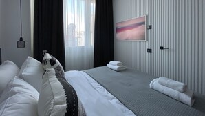 A modern hotel room with a large bed, a view of the city, and a painting on the wall. - Monastiraki 512 Superhost Hub (Athens)