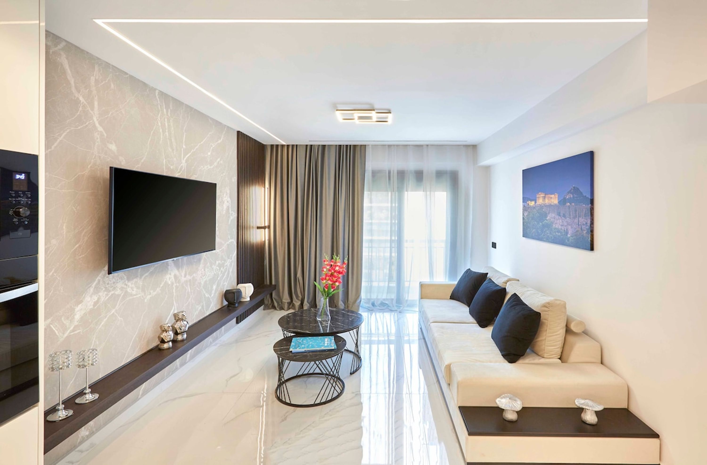 A modern living room with a flat-screen TV, a sofa, a coffee table, and a decorative vase.