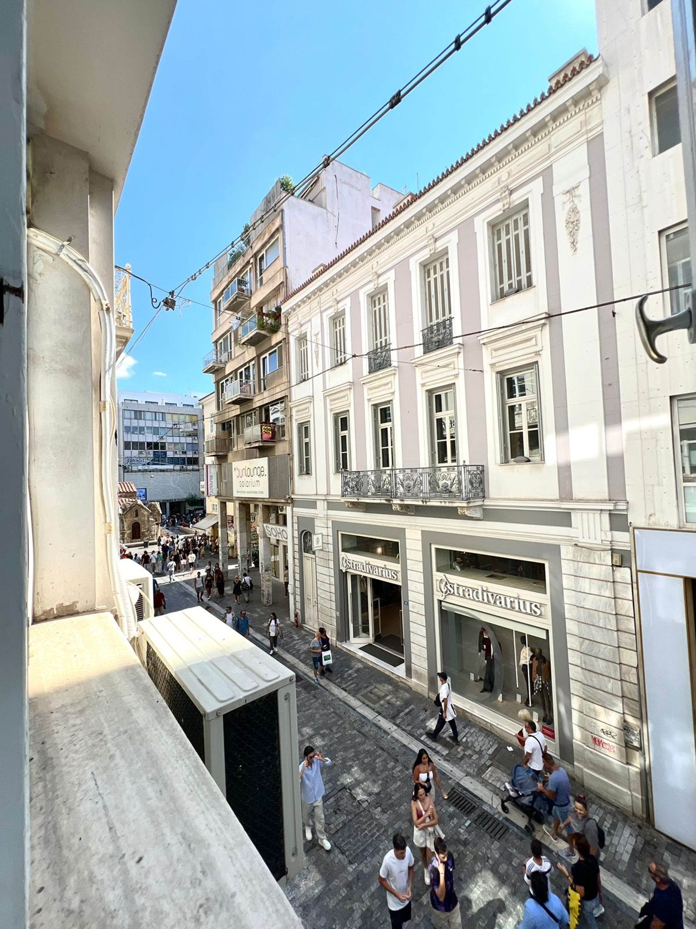 A street view with a building featuring storefronts with signage, including 'Stradivarius'.