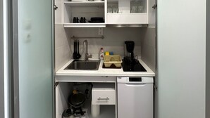 Cocina compacta con lavabo, cafetera y refrigerador pequeño.