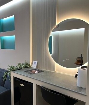 Een modern receptiebalie met een grote spiegel, een klein plantje en een welkomstbord.