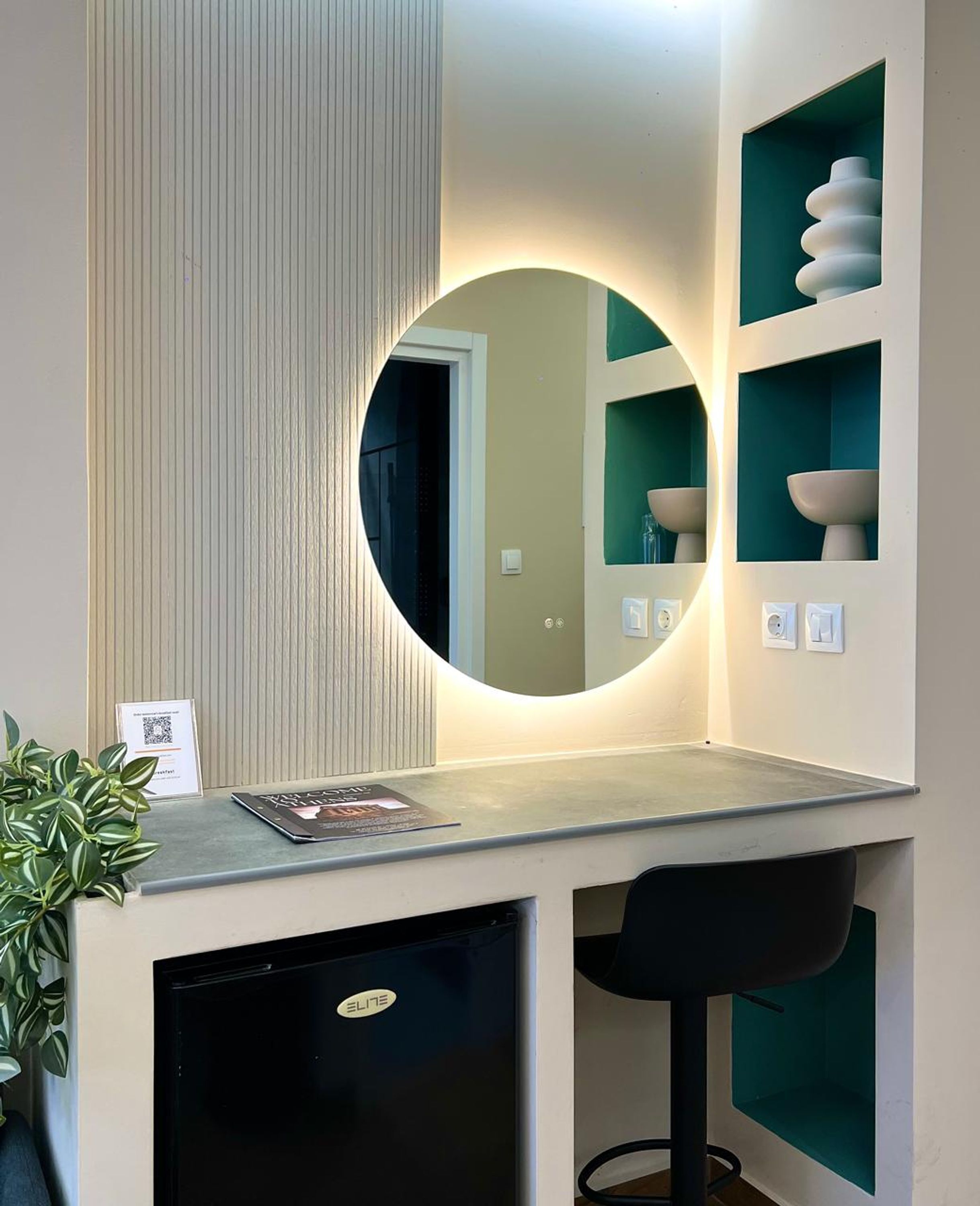 A modern bathroom with a round mirror, a sink, and a small cabinet.