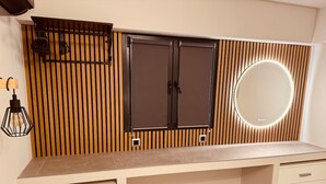 Een moderne slaapkamer met een groot bed, nachtkastjes en een spiegel aan de muur.
