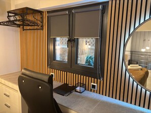 A modern bathroom with a wooden slat wall, a black vanity with a mirror, and a black chair.