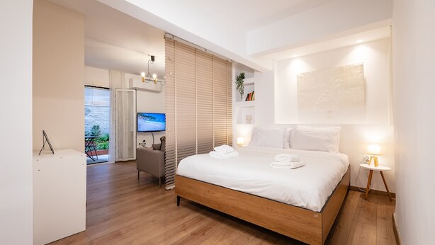Un dormitorio moderno con una cama de madera, un televisor y un balcón con vistas.