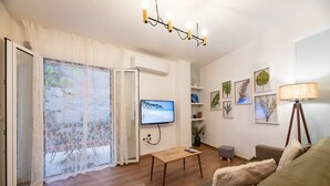 Una sala de estar con suelo de madera, televisor, sofá, mesa y lámpara.