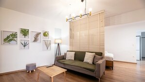 Una sala de estar moderna con piso de madera, un sofá gris, una pequeña mesa de madera e impresiones botánicas enmarcadas en la pared.