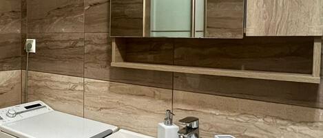 A modern bathroom with a built-in sink, a mirror, and a towel rack.