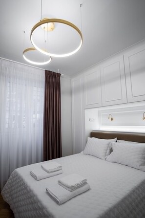 A hotel room with a large bed, white bedding, a headboard with a light fixture, and a window with sheer curtains. - Kaplanon Residence Kolonaki (Athens)