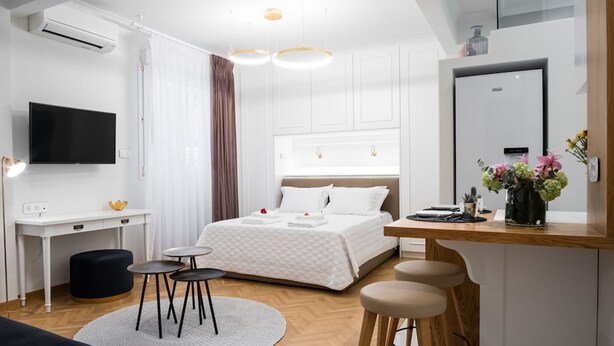 A modern hotel room with a bed, a desk, a chair, a mirror, and a TV. - Kaplanon Residence Kolonaki (Athens)