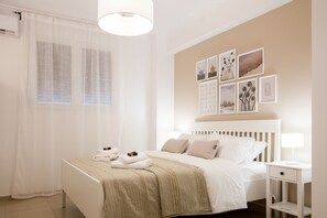 Une chambre d’hôtel avec un lit, une table de chevet, une lampe et des œuvres d’art accrochées au mur.