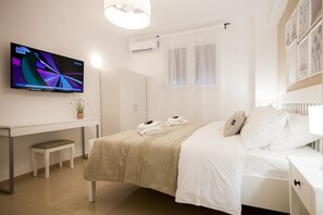 Une chambre d’hôtel moderne équipée d’un lit, d’une table de chevet et d’un téléviseur fixé au mur.