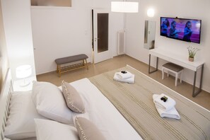 Une chambre d’hôtel avec un lit, une banquette, un bureau, une télévision et un radiateur.