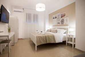 Une chambre à coucher moderne avec un lit, des tables de chevet, un bureau et un téléviseur.