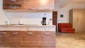 A modern kitchen with wooden cabinets, a coffee maker, and a red sofa in the living area.