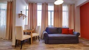 A living room with a sofa, chairs, a table, and a hanging light fixture.