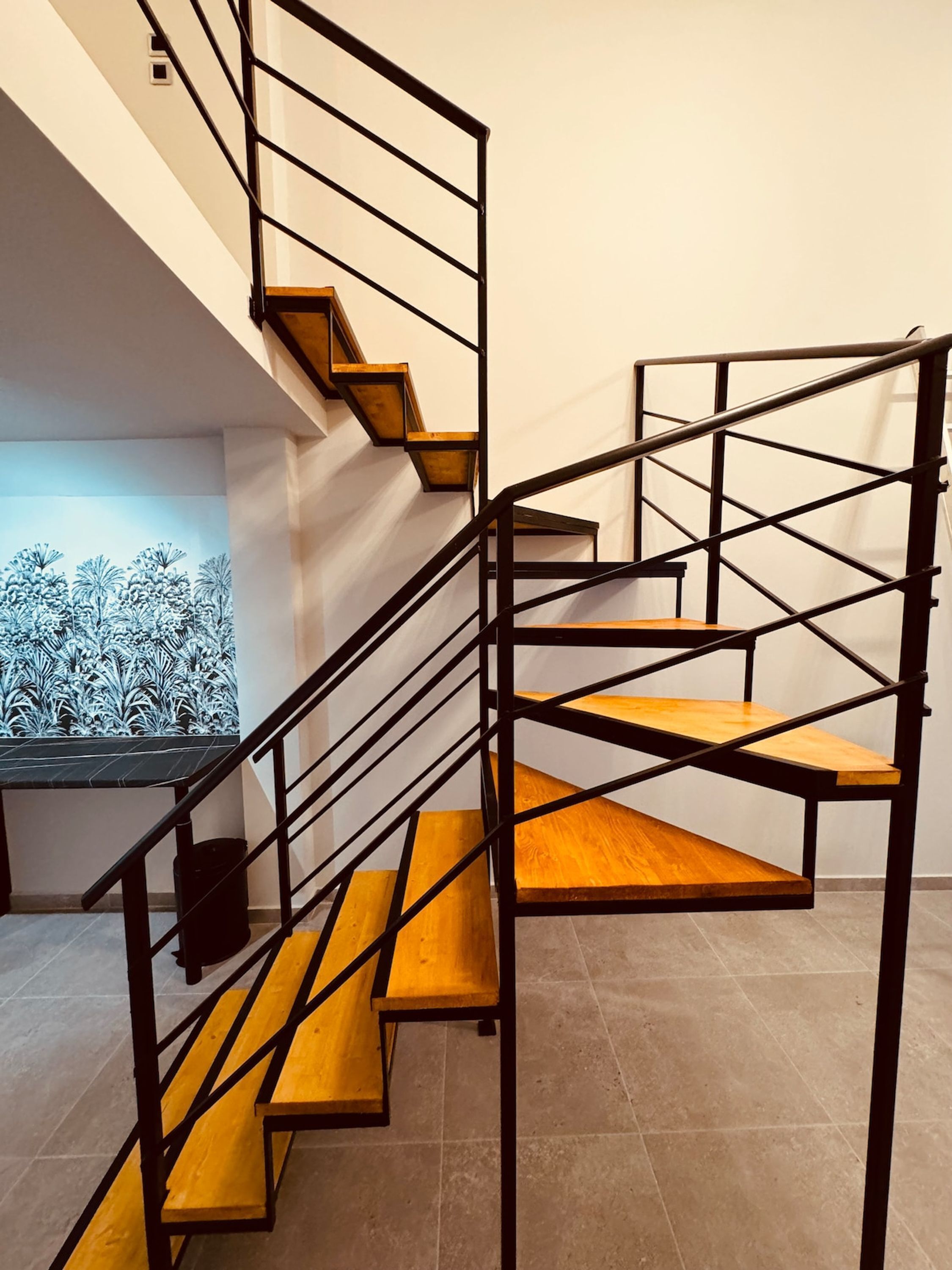 A spiral staircase with wooden steps and black metal railings.