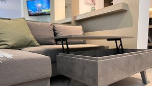 A modern living room with a grey sofa, a grey coffee table with a flat top, and a television mounted on the wall.