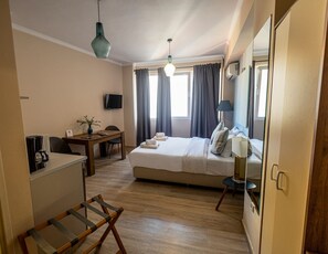 A hotel room with a bed, a desk with a coffee maker, a chair, a lamp, and a mirror. - Monastiraki 309 Superhost Hub (Athens)