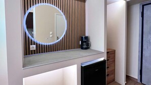 A modern bathroom with a built-in sink, a round mirror with a light, a coffee maker, and a black dishwasher. - Monastiraki 304 Superhost Hub (Athens)