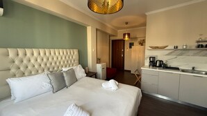 Habitació d'hotel amb un llit gran, una cuineta i una porta que dona a una altra habitació.