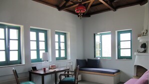 A cozy room with a wooden table, chairs, a bench with cushions, and a fireplace. - Gorgeous House Exclusive Location (Alonissos)