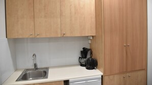A kitchen with wooden cabinets, a stainless steel sink, and a coffee maker. - Athens Ianos B by Super Host Hub (Athens)