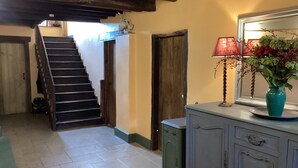 Una escalera que lleva a una puerta, un aparador con un jarrón y una lámpara.