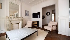 A living room with a marble coffee table, a fireplace, two armchairs, a television, and a mirror. - TheBlueStay 317 - Superb Apt near the Eiffel Tower (Paris)