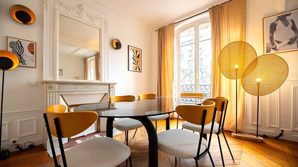 A dining room with a white table, six chairs, a fireplace, and large windows with curtains. - TheBlueStay 317 - Superb Apt near the Eiffel Tower (Paris)