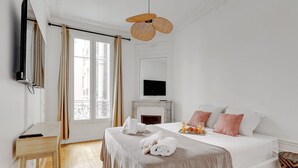 Ein Hotelzimmer mit Bett, Fernseher, Kamin und einem Fenster mit Vorhängen.