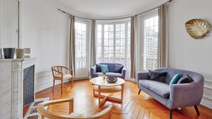 Un salon spacieux avec une cheminée, deux canapés, une table basse et une vue sur la ville grâce à de grandes fenêtres.