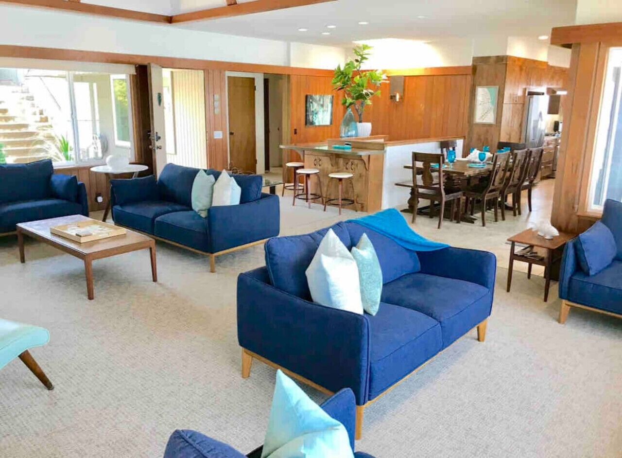 A spacious living area with blue sofas and a dining area with wooden furniture.