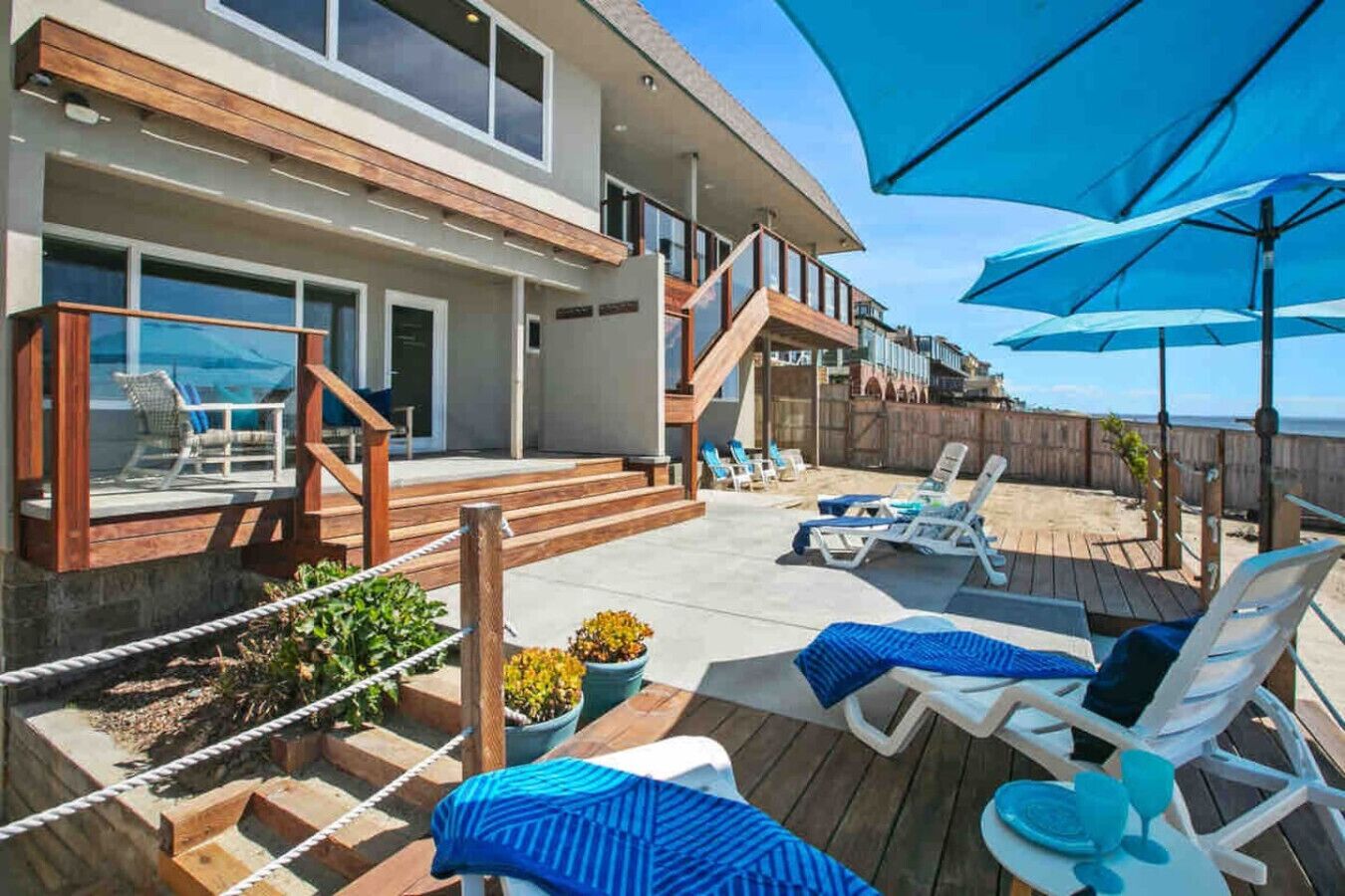 A modern house with a deck, outdoor seating, and a view of the ocean.