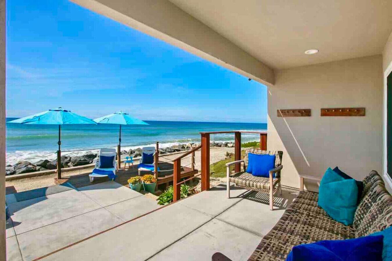 A balcony with a view of the ocean, outdoor seating, and a sofa with cushions.