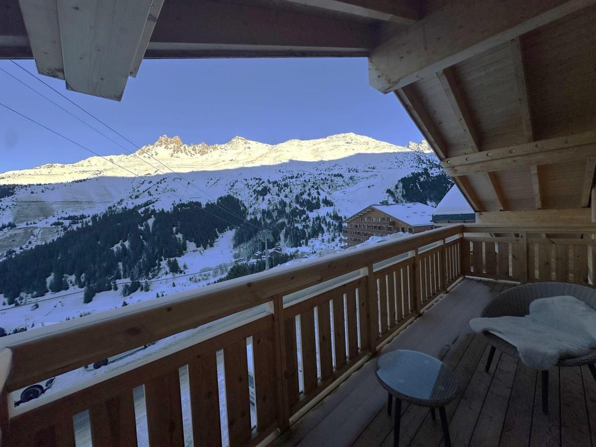 Eine Holzterrasse mit Blick auf schneebedeckte Berge und ein Gebäude im Hintergrund.
