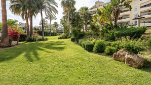 A well-maintained garden with palm trees, a grassy lawn, and various shrubs. - MalagaSuite Terrace&Pool Playamar (Torremolinos)