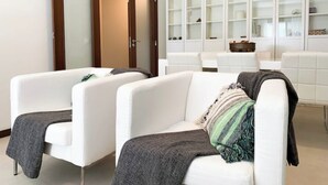 A modern living room with white sofas, a large wooden door, and a built-in shelving unit with glass doors. - Modern 2Bed Rooftop Pool & Gym, Marina & Half Beach (Lagos)