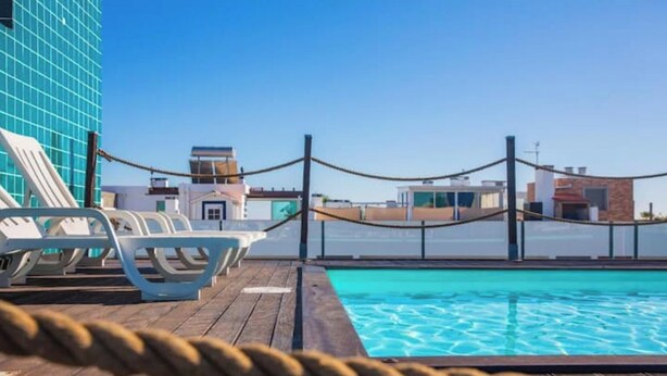 A poolside area with lounge chairs and a rope barrier. - Modern 2Bed Rooftop Pool & Gym, Marina & Half Beach (Lagos)