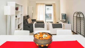 A modern living room with a sofa set, a dining table with a red placemat, a decorative bowl on the table, and a television on a stand. - Modern 2Bed Rooftop Pool & Gym, Marina & Half Beach (Lagos)