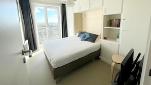 A bedroom with a bed, a desk, a chair, a bookshelf, and a window with curtains. - Apartment by Belgian Coast With Sea View (Middelkerke)