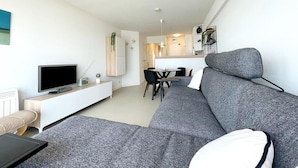 A modern living room with a grey sofa, a flat-screen TV, and a minimalist design. - Apartment by Belgian Coast With Sea View (Middelkerke)