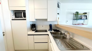 A compact kitchen with white cabinets, a microwave, a coffee maker, and a sink. - Apartment by Belgian Coast With Sea View (Middelkerke)