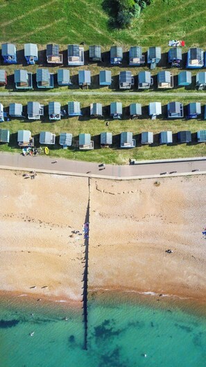 A series of uniform, rectangular structures arranged in rows on a grassy field, adjacent to a sandy beach with clear water. - *New* | St James - City Centre Modern Apartment (Canterbury)