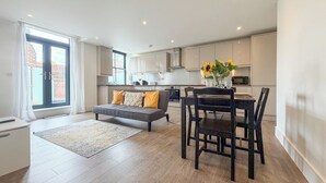 A modern apartment with a dining area, kitchen, and a large window.