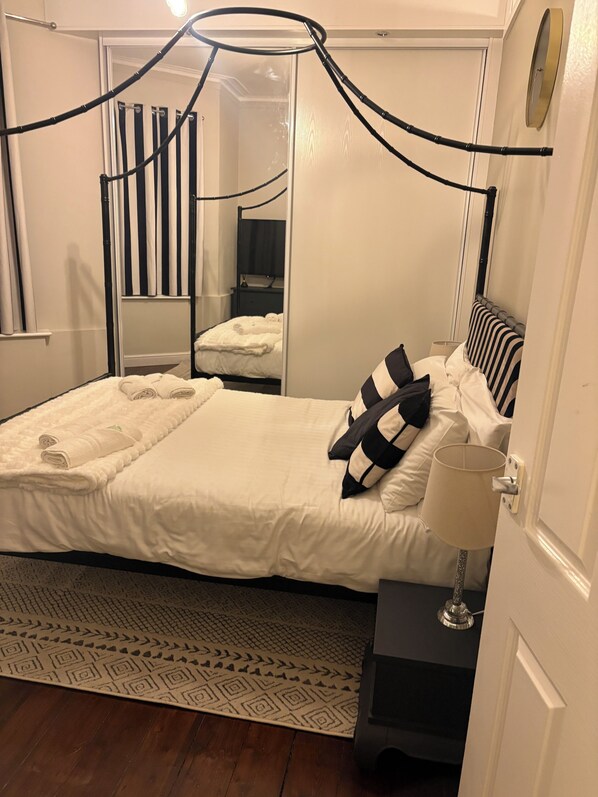 Restful retreat with a large bed, mirror, and bedside table.