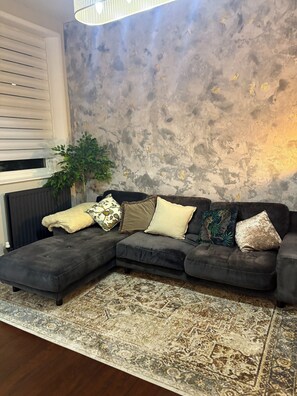 Relax in this stylish living room with a comfortable sectional sofa, patterned rug, and a potted plant.
